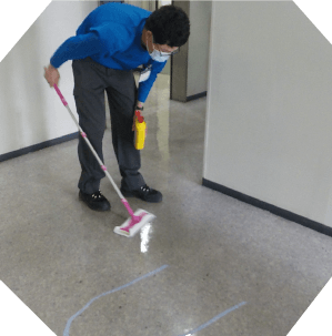 屋内でフローリングワイパーを使い掃除をしている場面